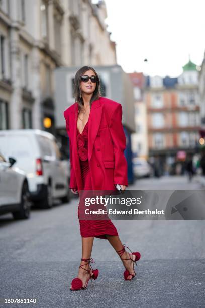 Darja Barannik wears black sunglasses, a red oversized blazer jacket, a red wrap V-neck / embroidered flower pattern chest long dress, red strappy...