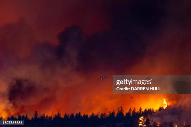 Helicopter battles the McDougall Creek wildfire as it burns in the hills West Kelowna, British Columbia, Canada, on August 17 as seen from Kelowna....