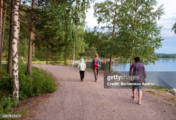 family of caucasians on an evening walk along the lake. an elderly woman, a girl of 8 years old and a young woman spend time together on vacation. - 40 44 years woman caucasian stockfoto's en -beelden