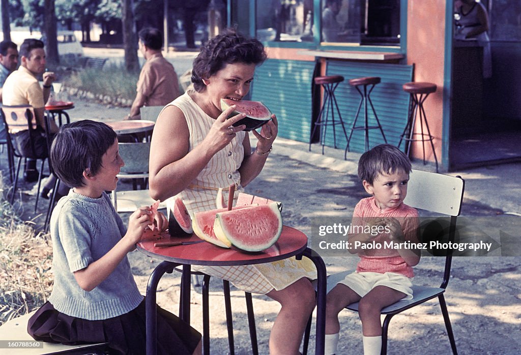 Mother and two children eating watermelon outdoors