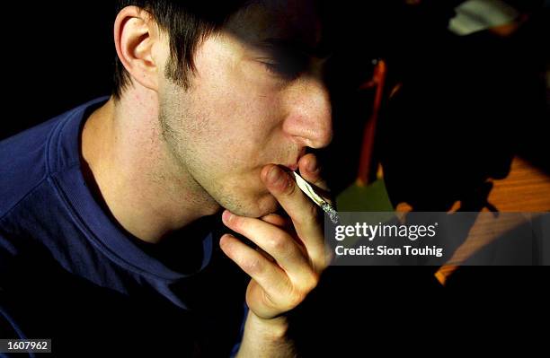 Man smokes marijuana at his home August 8, 2001 in the Dalston section of East London. Cannabis use in the United Kingdom is still illegal, but it''...