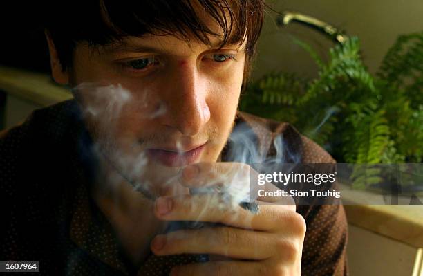 Man smokes marijuana at his home August 8, 2001 in the Dalston section of East London. Cannabis use in the United Kingdom is still illegal, but it''...