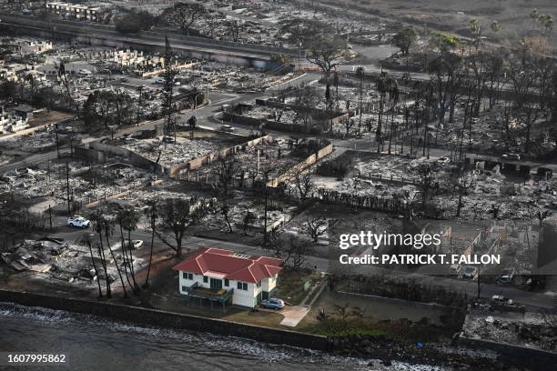 An aerial image shows a red roofed house that survived the fires surrounded by destroyed homes and buildings burned to the ground in the historic...