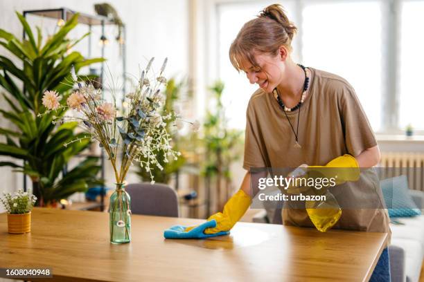 mujer joven limpiando la superficie de la mesa del comedor - home cleaning fotografías e imágenes de stock