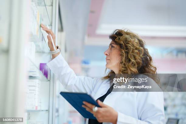 farmacéutico usando una tableta digital para hacer inventario en una farmacia - industria farmaceutica fotografías e imágenes de stock