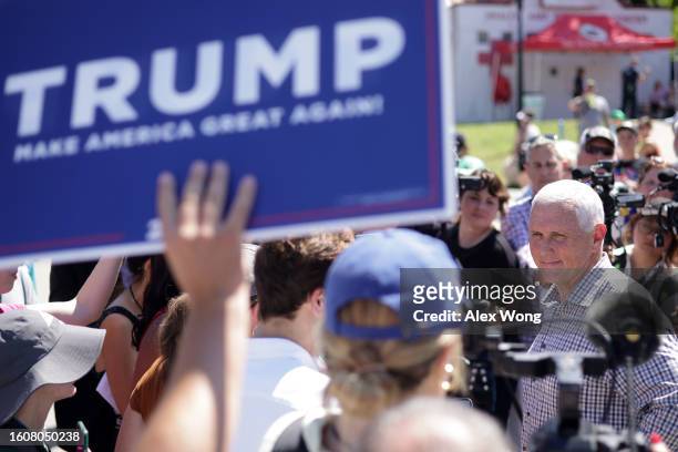 Republican U.S. Presidential candidate and former Vice President Mike Pence speaks to members of the press as a Trump supporter holds up a Trump...