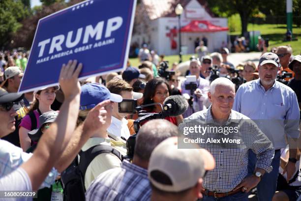 Republican U.S. Presidential candidate and former Vice President Mike Pence speaks to members of the press as a Trump supporter holds up a Trump...