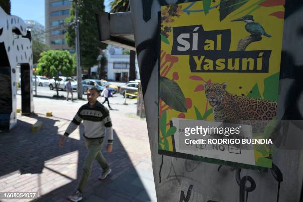 Man passes next to an advertisement supporting the halting of the exploitation of crude oil in an important block of the Yasuni National Park in...