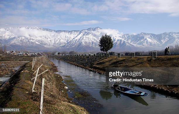 Boatman rows his boat through a canal during a sunny day, on February 6, 2013 in Srinagar, India. After two days of intermittent snow and rain...