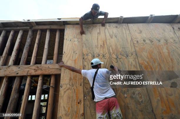 Restaurant employees put protective wood planks at a restaurant near the beach before the arrival of hurricane Hilary at Los Cabos resort in Baja...