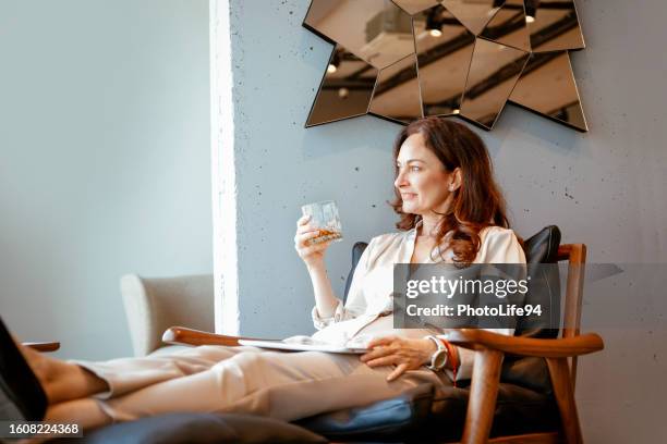 satisfied pretty woman relaxing in cozy armchair - whiskey stock pictures, royalty-free photos & images
