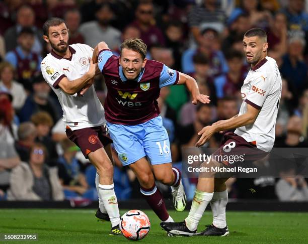 Sander Berge of Burnley is challenged by Bernardo Silva and Mateo Kovacic of Manchester City during the Premier League match between Burnley FC and...