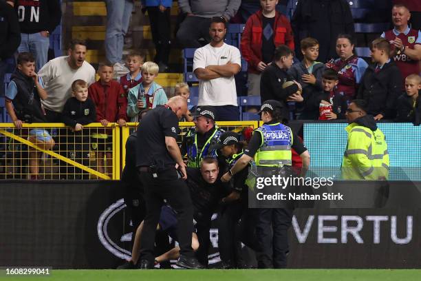 Spectator is arrested by the police after attempting to run on the pitch during the Premier League match between Burnley FC and Manchester City at...