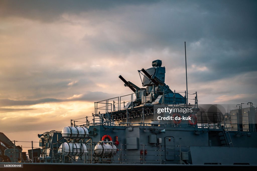 Military carrier turrets and weapons on warship at sunset close-up