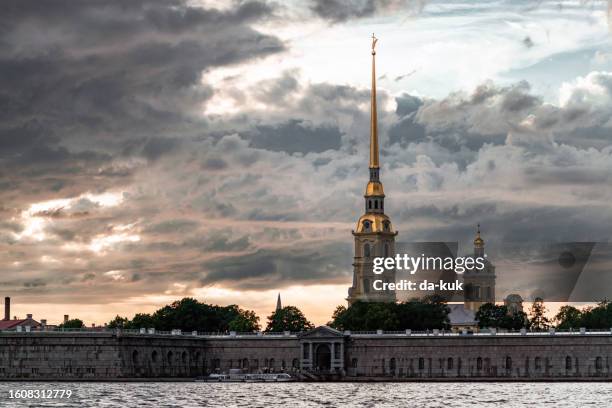 peter and paul fortress seen from neva river. dramatic clouds and sky at sunset on the background. st. petersburg - neva river stock pictures, royalty-free photos & images