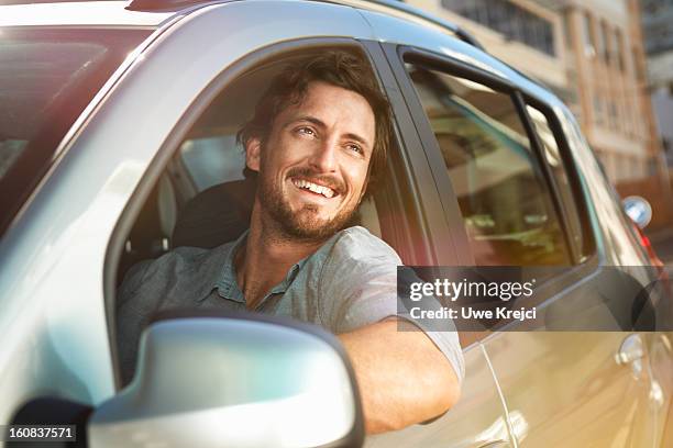 young man looking out of car window - drive happy foto e immagini stock
