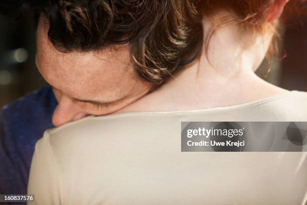 man resting his head on woman's shoulder - couple embrace stock-fotos und bilder