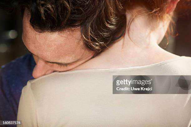 man resting his head on woman's shoulder - back of womens heads stockfoto's en -beelden