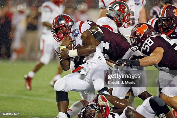 Running back Savon Huggins of the Rutgers Scarlet Knights is tackled by safety Detrick Bonner of the Virginia Tech Hokies during the Russell Athletic...