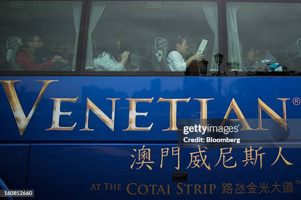 Passengers sit in a shuttle bus for the Venetian Macao resort and casino, operated by Sands China Ltd., a unit of Las Vegas Sands Corp., in Macau,...