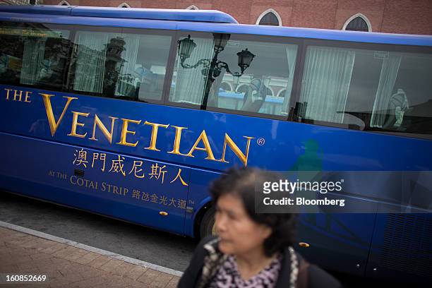 Woman walks past a shuttle bus for the Venetian Macao resort and casino, operated by Sands China Ltd., a unit of Las Vegas Sands Corp., in Macau,...