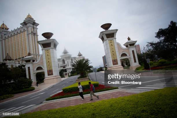 Two men walk past the entrance to Galaxy Entertainment Group Ltd.'s Galaxy Macau casino resort in Macau, China, on Wednesday, Feb. 6, 2013. Casino...