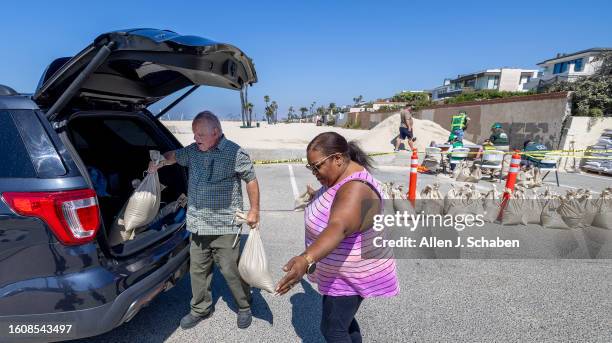 Seal Beach, CA John Straub, left, a volunteer with West Orange County Community Emergency Response Team loads sandbags for Cynthia Abernathy, of...