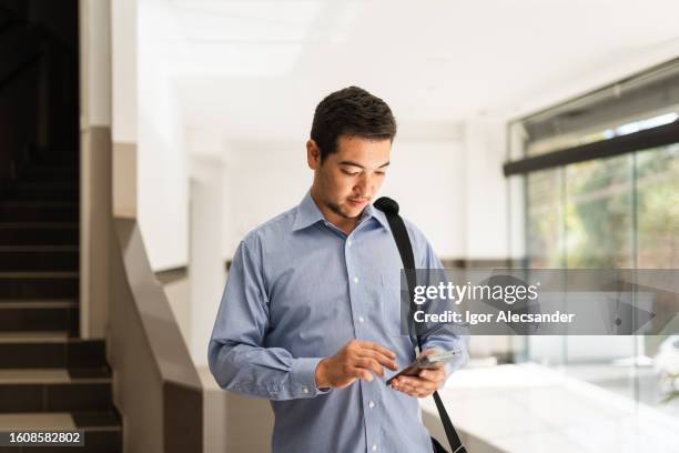 giovane uomo d'affari che utilizza lo smartphone nel corridoio - real people foto e immagini stock