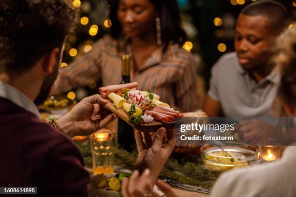 friends enjoying drinks, delicious food and chatting casually during a christmas dinner party - charcuterie stock pictures, royalty-free photos & images