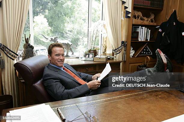 Rendezvous With Arnold Schwarzenegger. Attitude souriante d'Arnold SCHWARZENEGGER, en costume d'homme d'affaires et santiags de cow-boy, les pieds...