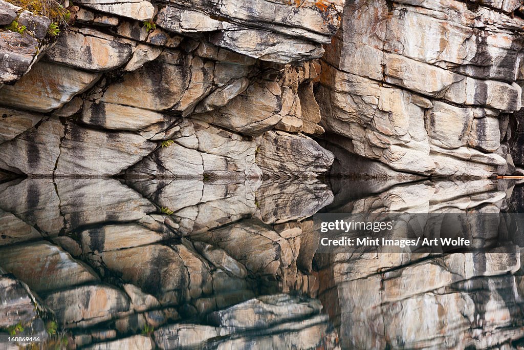 Rocky cliffs reflected in the calm waters of Horseshoe Lake, Jasper National park, Alberta, Canada.