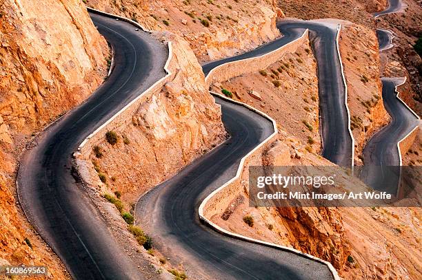 winding road with hairpin bends up the rocky atlas mountains from the dades valley, morocco - atlas mountains stock-fotos und bilder