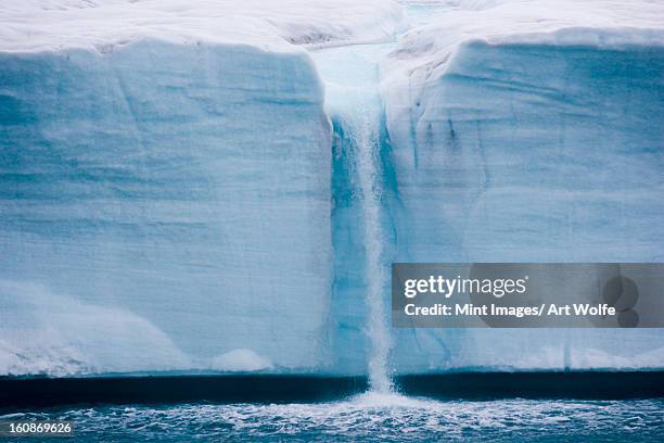 a waterfall is created by a melting iceberg, svalbard, norway - eis schmelzen stock-fotos und bilder