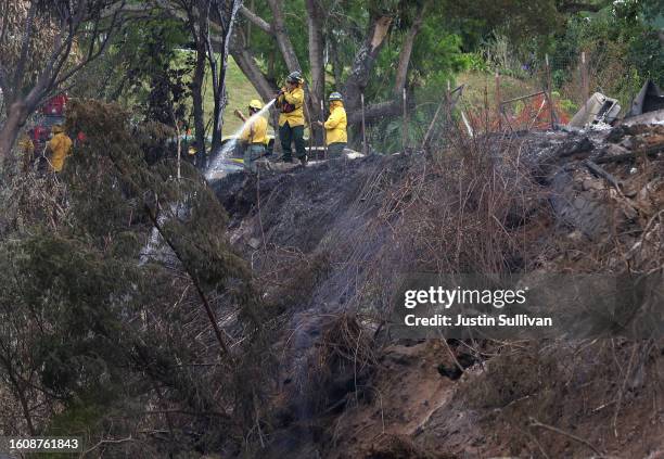 Firefighters mop up hot spots near a home that was destroyed by a wildfire on August 11, 2023 in Kula, Hawaii. Dozens of people were killed and...