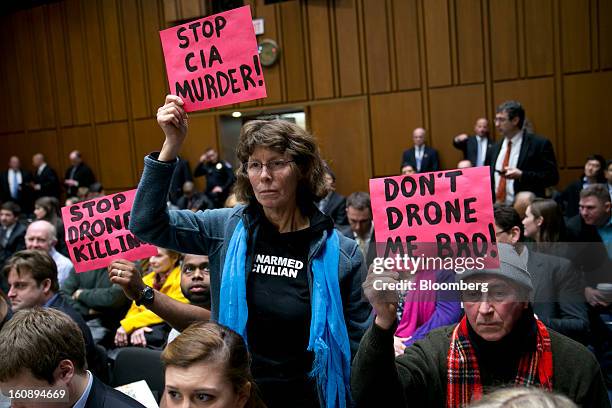 Demonstrators Max Obuszewski, right, and Helen Schietinger hold up signs in protest before a Senate Select Intelligence Committee nomination hearing...