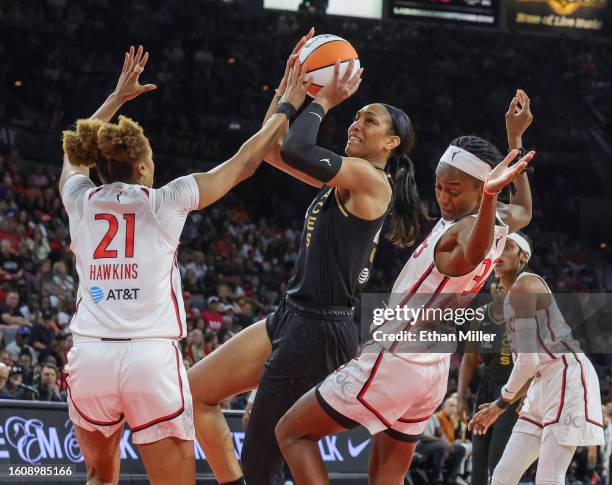 Ja Wilson of the Las Vegas Aces drives to the basket against Tianna Hawkins and Shatori Walker-Kimbrough of the Washington Mystics in the fourth...