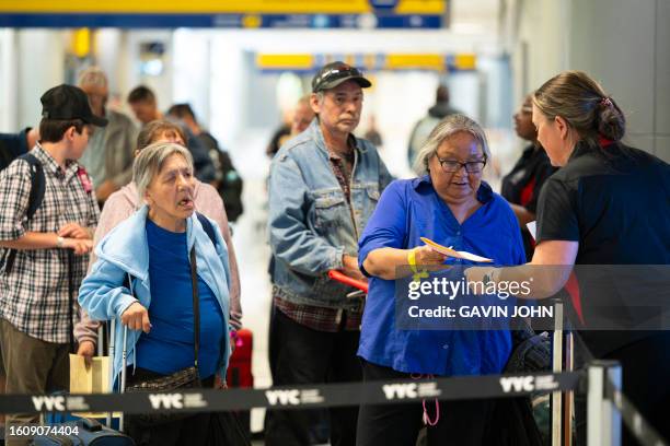 Yellowknife evacuee Martha Kanatsiak hands paperwork to a City of Calgary worker at the registration office in the Calgary Airport, Alberta on August...