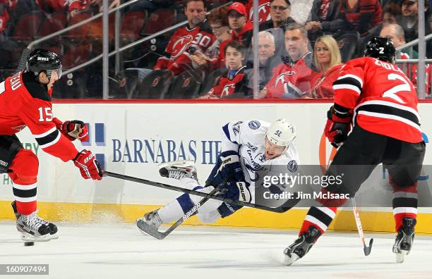 Dana Tyrell of the Tampa Bay Lightning plays the puck in the first period against Stefan Matteau and Marek Zidlicky of the New Jersey Devils at the...