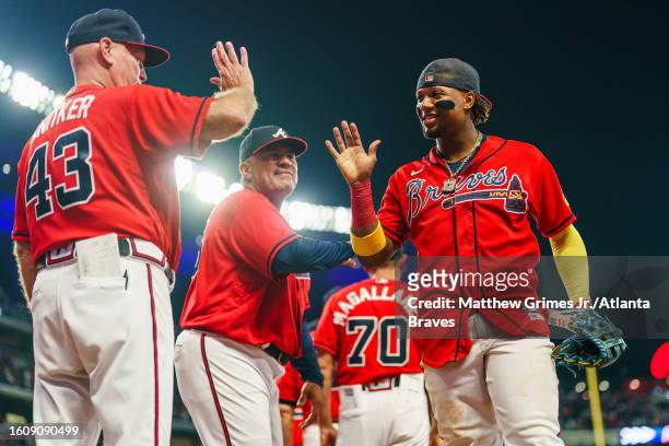 Ronald Acuna Jr. #13 of the Atlanta Braves gives a high five to Brian Snitker after winning the game against the San Francisco Giants 4-0 at Truist...
