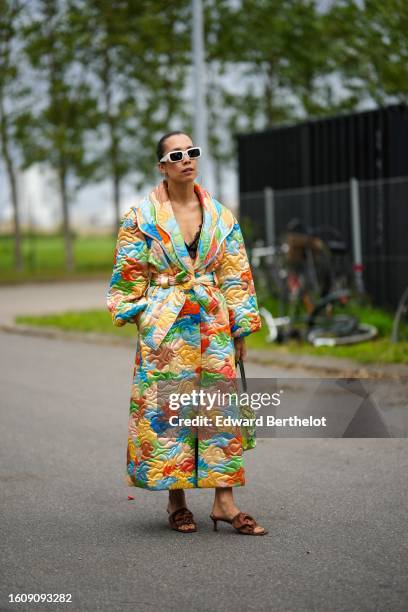 Guest wears white plastic squared sunglasses from Prada, gold earrings, a black lace cut-out pattern bra V-neck underwear, a multicolored print...