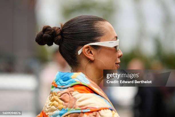 Guest wears white plastic squared sunglasses from Prada, gold earrings, a black lace cut-out pattern bra V-neck underwear, a multicolored print...