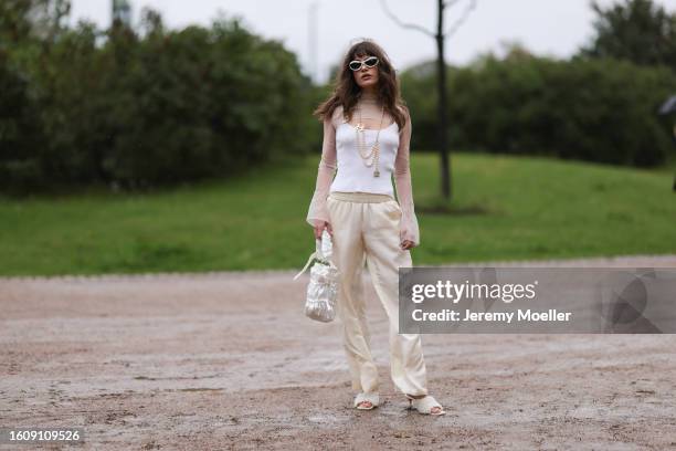 Lea Naumann seen wearing silver Mango sunnies, Ritual Unions see through top, Opera Sport tank top, Chanel pearl necklace, gold shiny silk pants,...