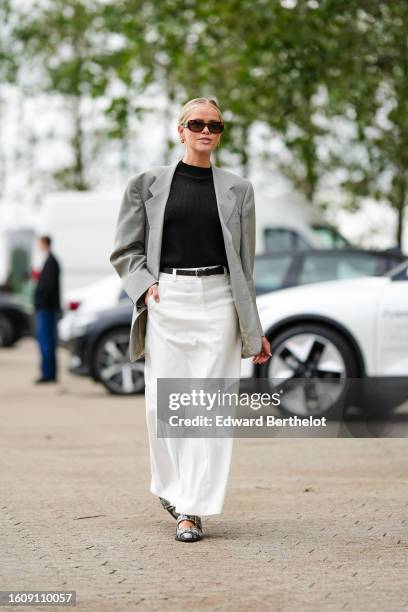 Guest wears black marble pattern sunglasses from Chanel, gold earrings, a black turtleneck ribbed pullover, a pale gray oversized blazer jacket, a...