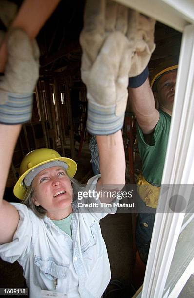 Sue Cary, a volunteer with the Epiphany Church of Seattle, installs weather stripping in a Habitat for Humanity home with the help of Wells Fargo...