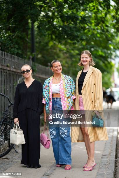 Guest wears black sunglasses, a black V-neck long sleeves shirt, black large suit pants, a white shiny leather Birkin handbag from Hermes, black...