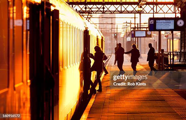 passengers boarding train at sunset - train transportation stock pictures, royalty-free photos & images