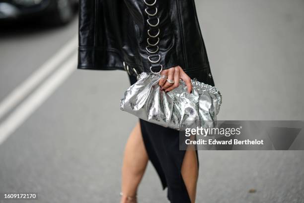 Guest wears a black cut-out waist long tube dress, a black shiny leather long zipper jacket with embroidered large silver ring on the sleeves slides...