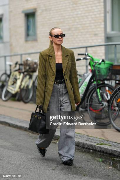 Guest wears black sunglasses, a black shoulder-off body, a yellow and black small houndstooth print pattern long blazer jacket, a black shiny leather...