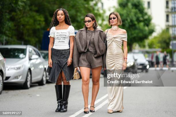 Guest wears a white ribbed short puffy sleeves t-shirt with black inscriptions slogan "We Have Nothing To Lose But Our Chains" pattern, silver...