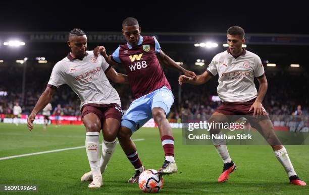 Lyle Foster of Burnley is challenged by Manuel Akanji and Rodri of Manchester City during the Premier League match between Burnley FC and Manchester...